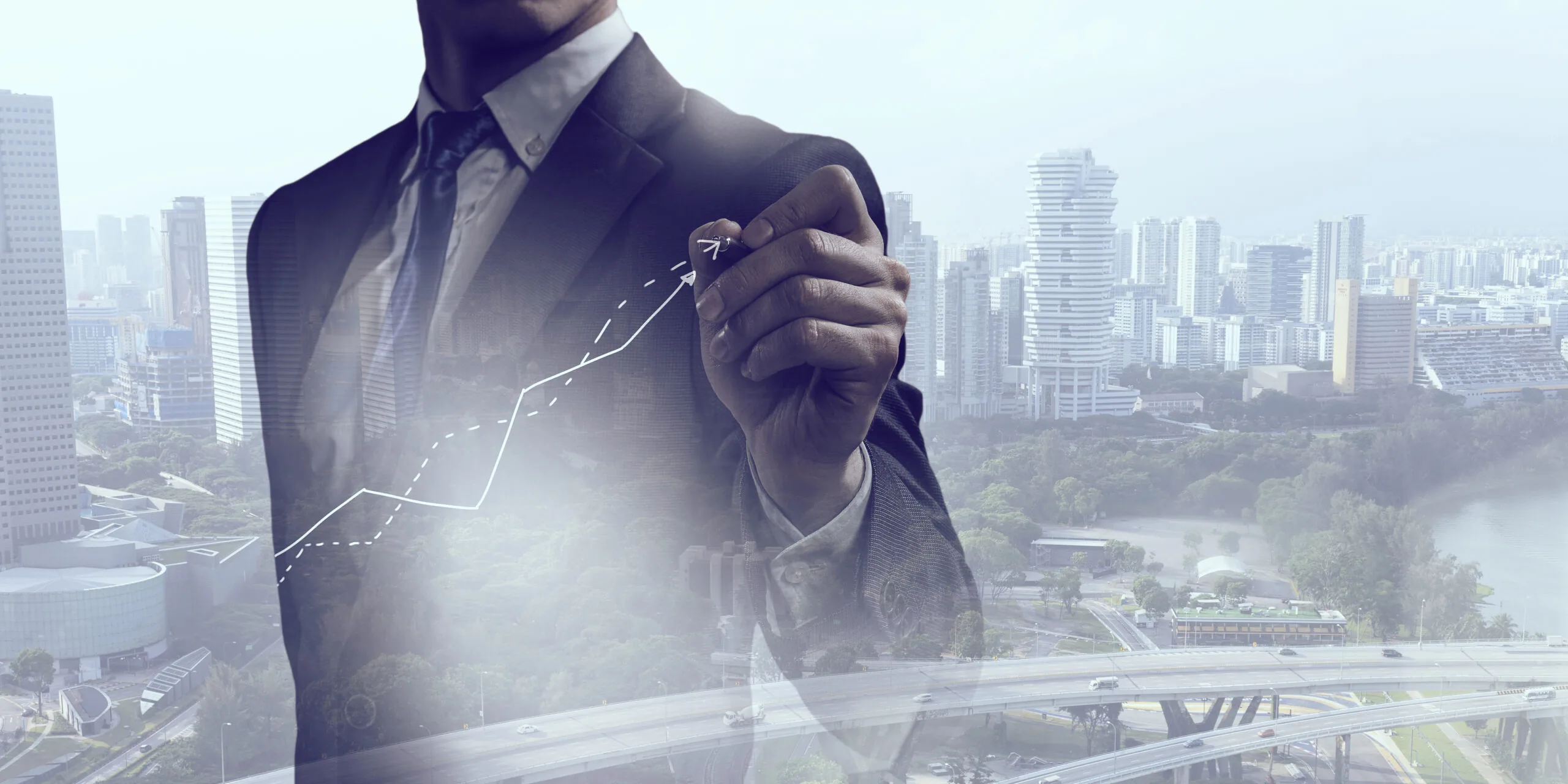 Business professional drawing an upward financial chart over a city skyline.